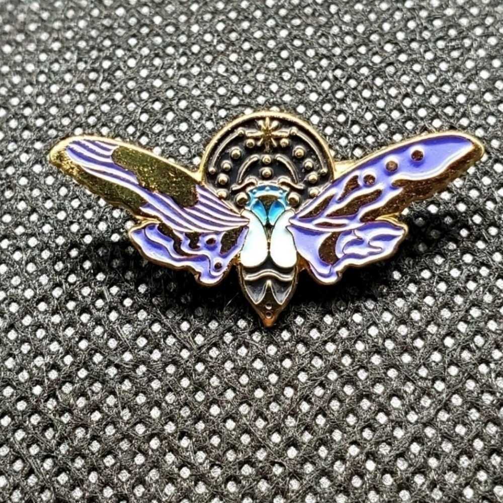 Glow in the dark flying beetle enamel pin.